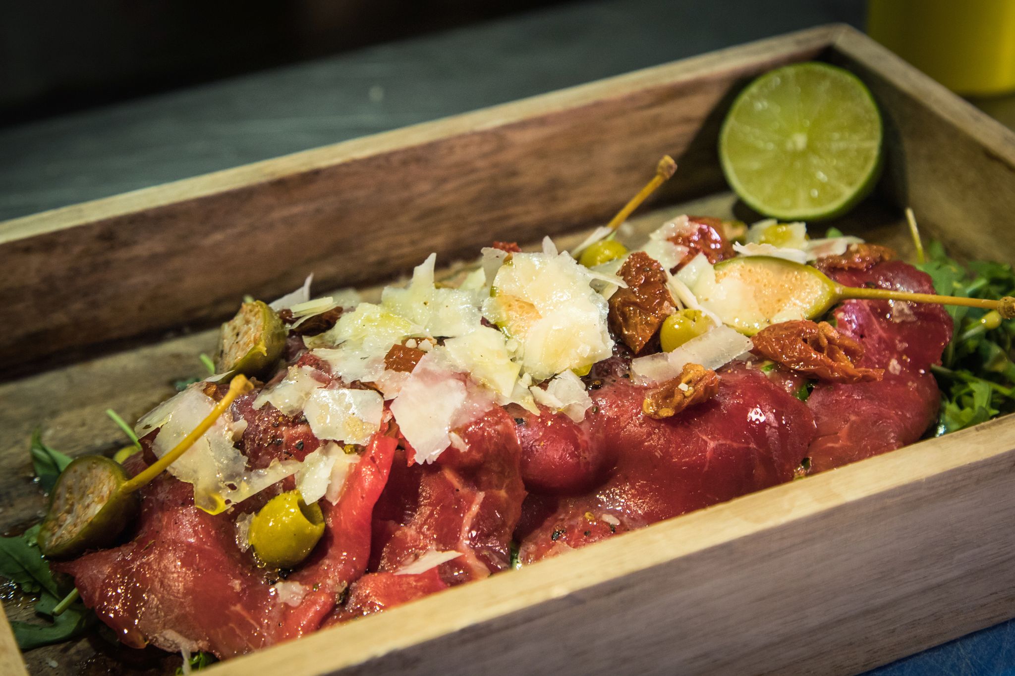 Statt auf dem runden Teller wird das Carpaccio im «The Dry Gin and Beef Club» auf einem kleinen Tablett auf Rucola angerichtet. Limette träufelt der Gast zum Schluss selbst darüber.