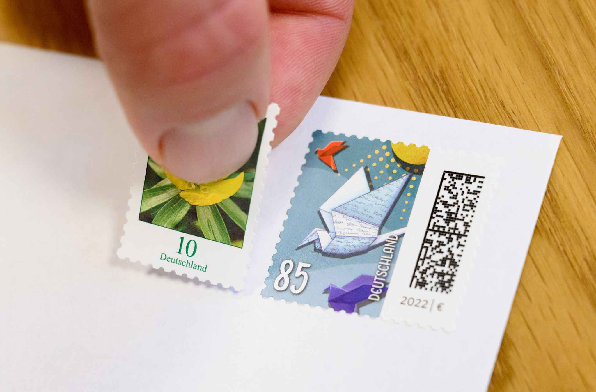 Eine 10-Cent-Briefmarke wird neben eine 85-Cent-Briefmarke geklebt (gestellte Szene).