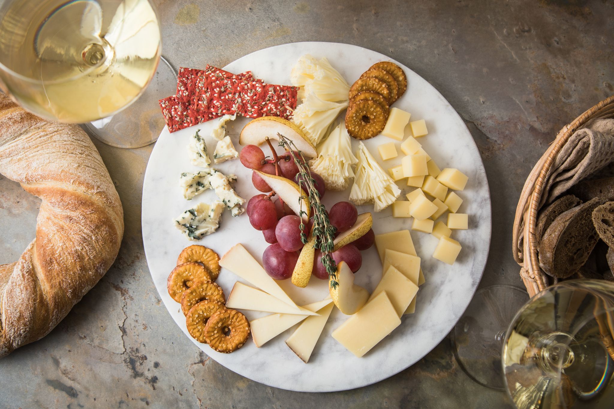 Eine Käseplatte nach der Uhr gestellt: Um 12 Uhr beginnt es mild mit Tête de Moine, wird mit Emmentaler, Le Gruyere und Appenzeller immer herzhafter und schließt zwischen 9 und 11 Uhr mit würzigem Blauschimmelkäse. Trauben, Birnenspalten, Thymian, Rote-Bete- und Brezel-Chips lockern die Platte auf.