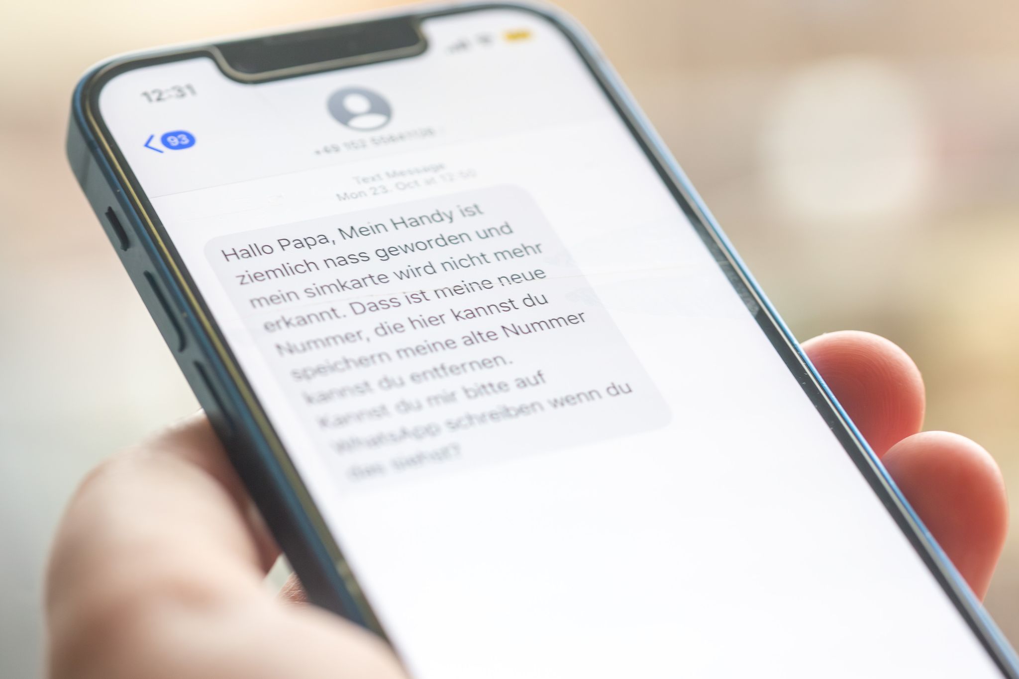 Eine Frau hält ein Smartphone in ihrer Hand, auf dessen Display eine Betrugs-SMS zu lesen ist.