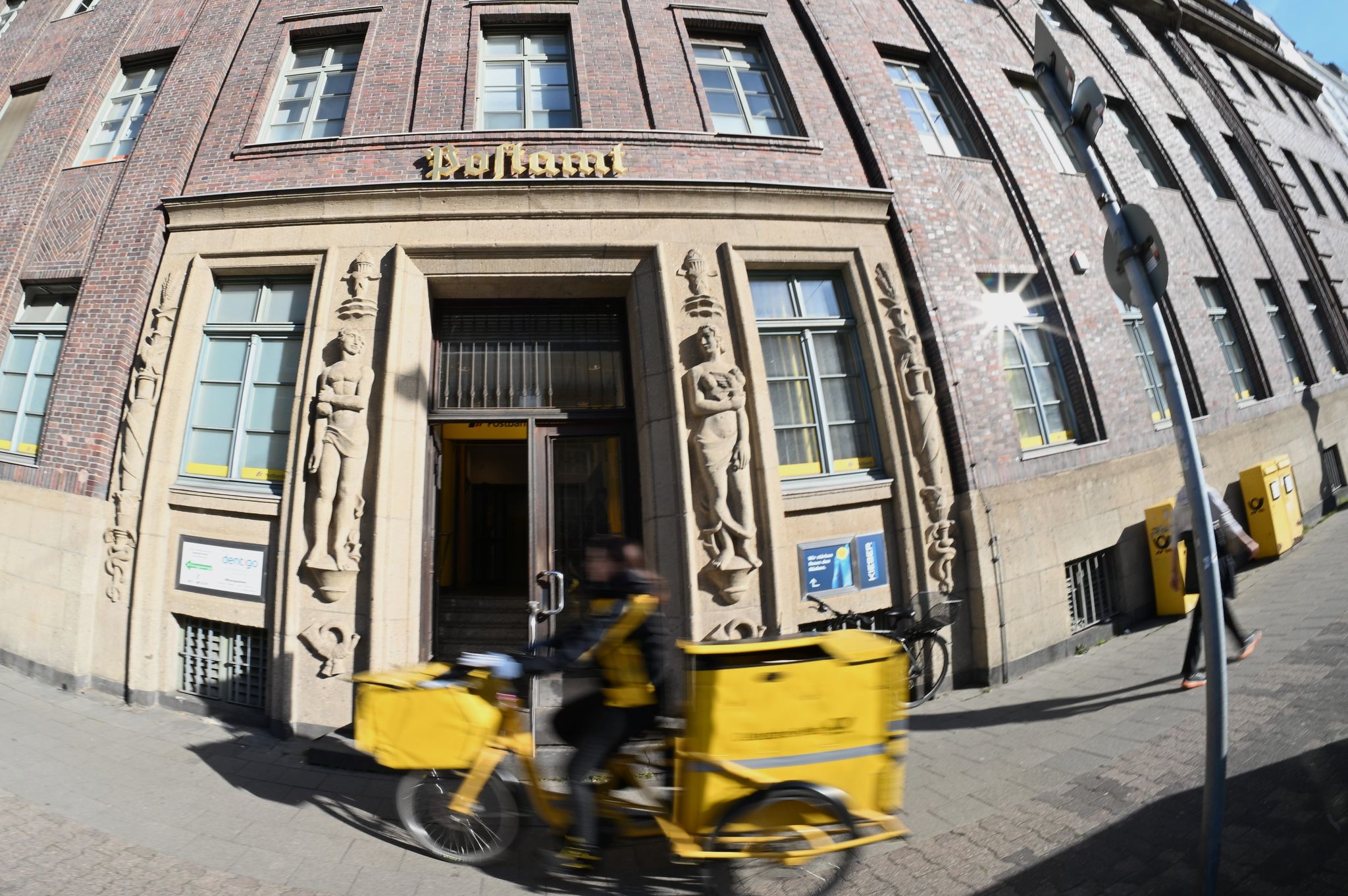 Eine Briefträgerin fährt an einer Postfiliale vorbei - vielleicht ist auch sie eine Beamtin?