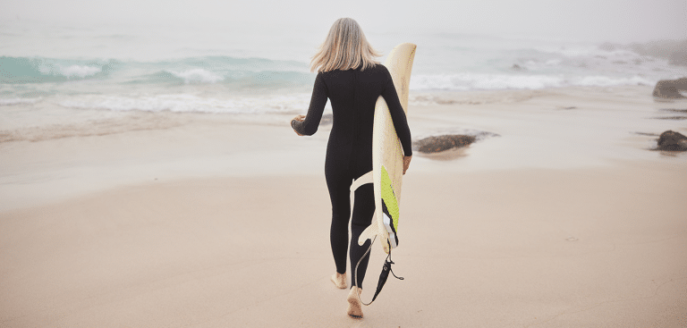 Frau mit Surfbrett - Goodboy Picture Company/iStock