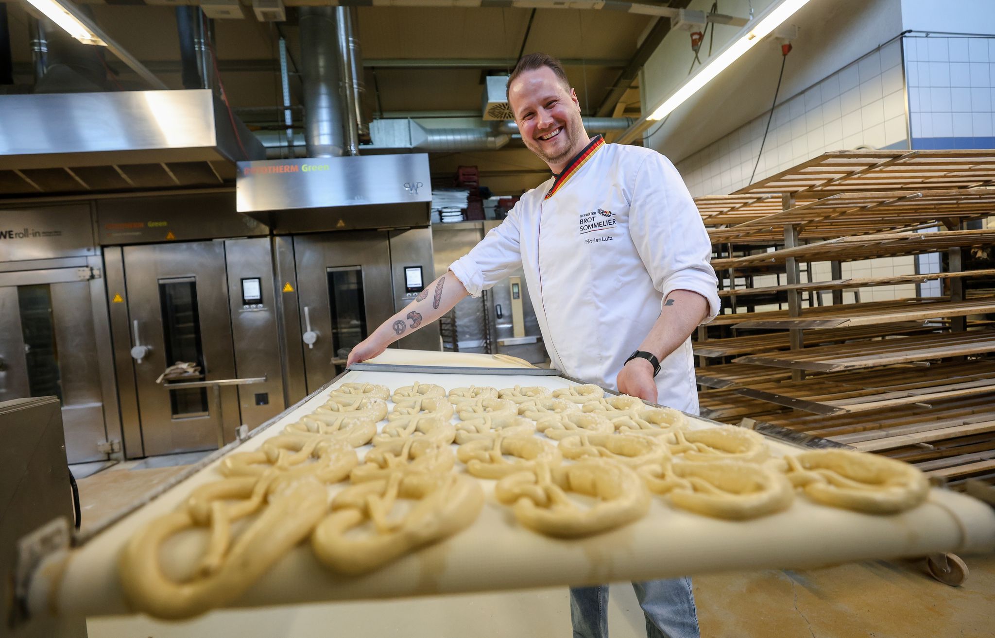 Backen ist Kunst: Brot-Sommelier Florian Lutz steht in seiner Backstube und schiebt ein Blech Brezeln in den Ofen.
