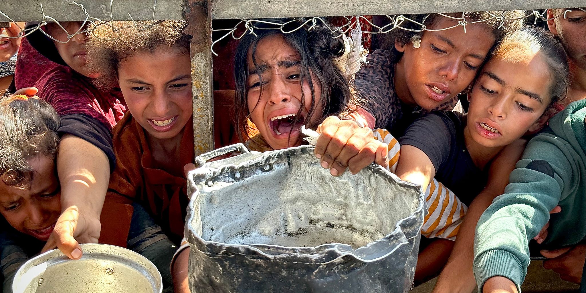 Palästinensische Kinder versuchen im Gebiet Al-Mawasi im Gazastreifen, mit ihren Töpfen Nahrungsmittel zu bekommen, die von Wohltätigkeitsorganisationen verteilt werden.