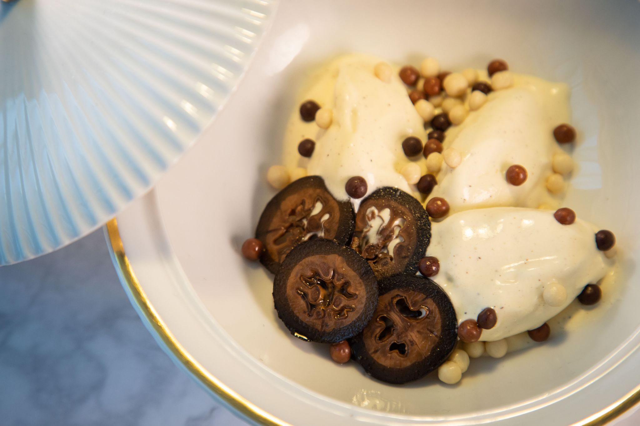 Schwarze Walnüsse in feine Scheiben geschnitten geben dem Vanilleeis mit Schokoladenkugeln einen Extra-Kick.