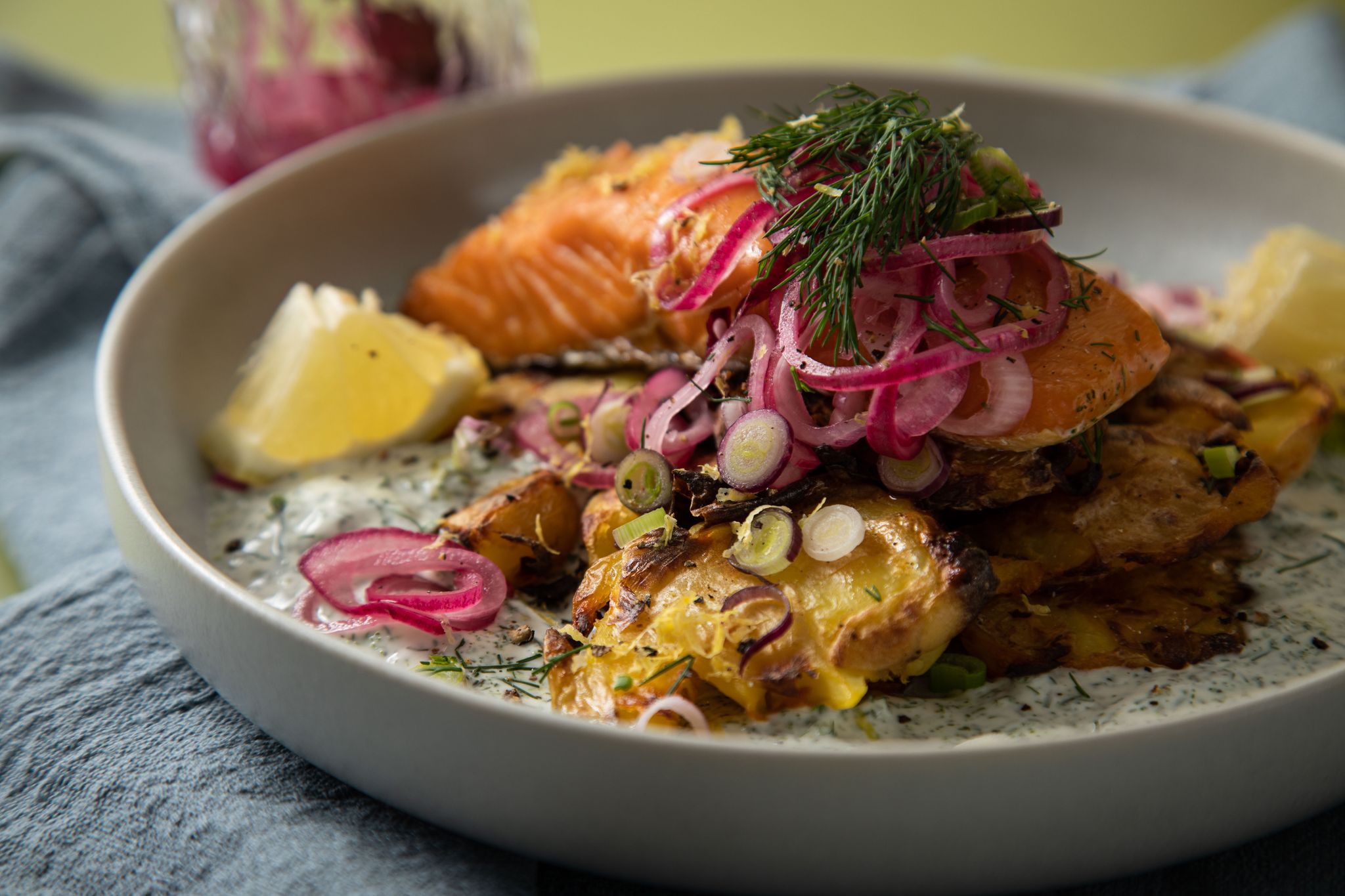Eingelegte rote Zwiebeln toppen den Schweden-Salat mit crispy smashed Potatoes und Lachs.
