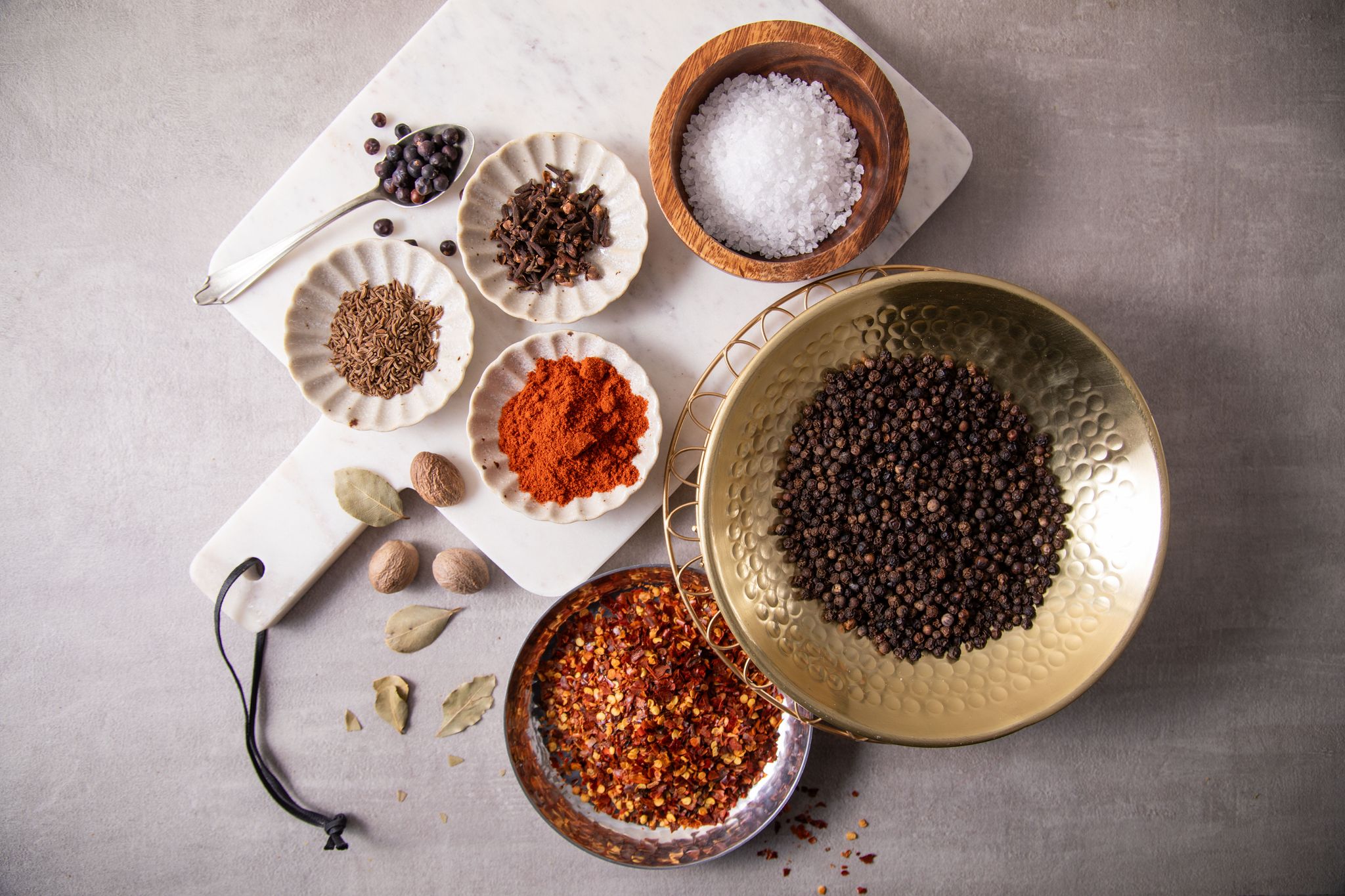 Zur Grundausstattung in der Küche gehören Salz, schwarzer Pfeffer, Chili-Flocken, Paprika edelsüß oder geräuchert, Kümmel, Nelken, Wachholderbeeren, Lorbeer und Muskatnuss.