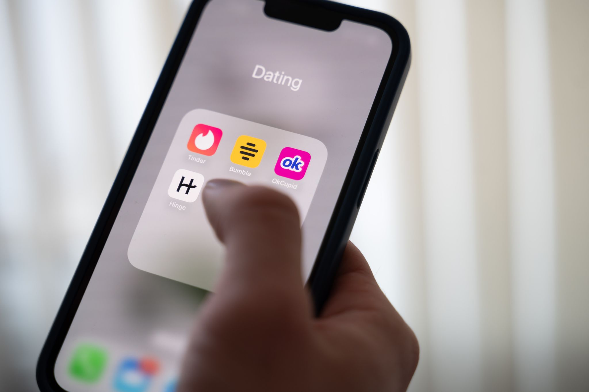 Eine Frau hält ein Smartphone, auf dem Dating-Apps angezeigt werden. (Symbolbild)