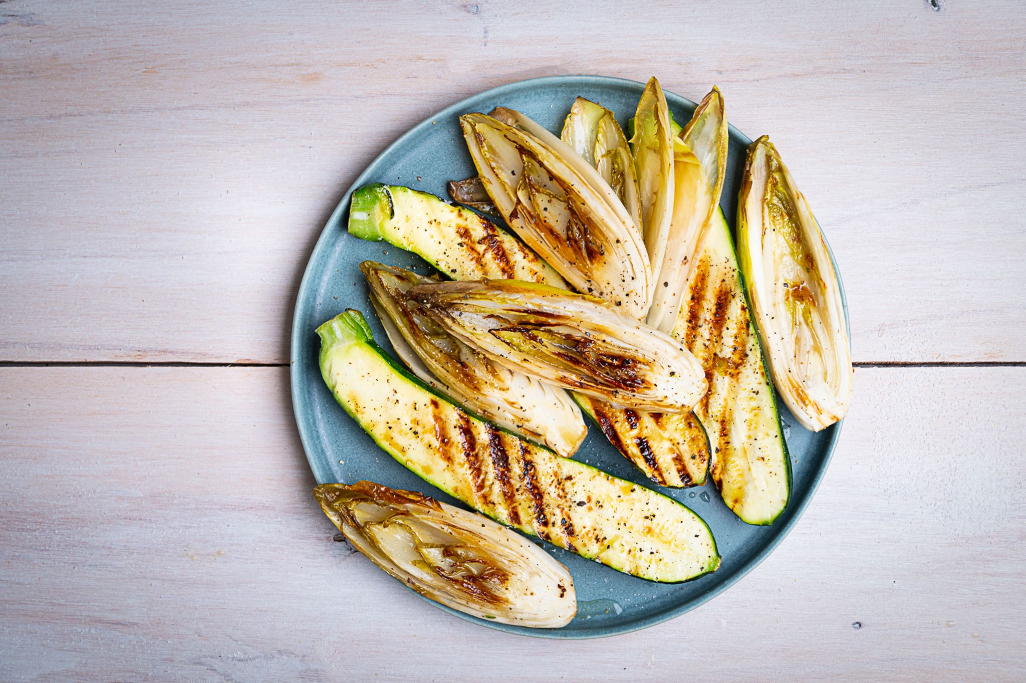 Die länglich geschnittenen Zucchini- und Chicorée-Streifen werden mit einer Marinade aus Olivenöl, Limettensaft, Salz und Pfeffer eingepinselt, dann auf jeder Seite 2–3 Minuten gegrillt.