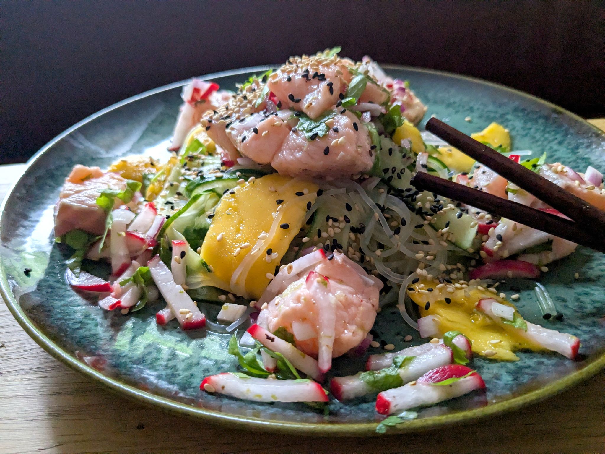 Der Glasnudelsalat mit Lachs-Ceviche wird mit gerösteten weißen und schwarzen Sesamkörnchen getoppt.