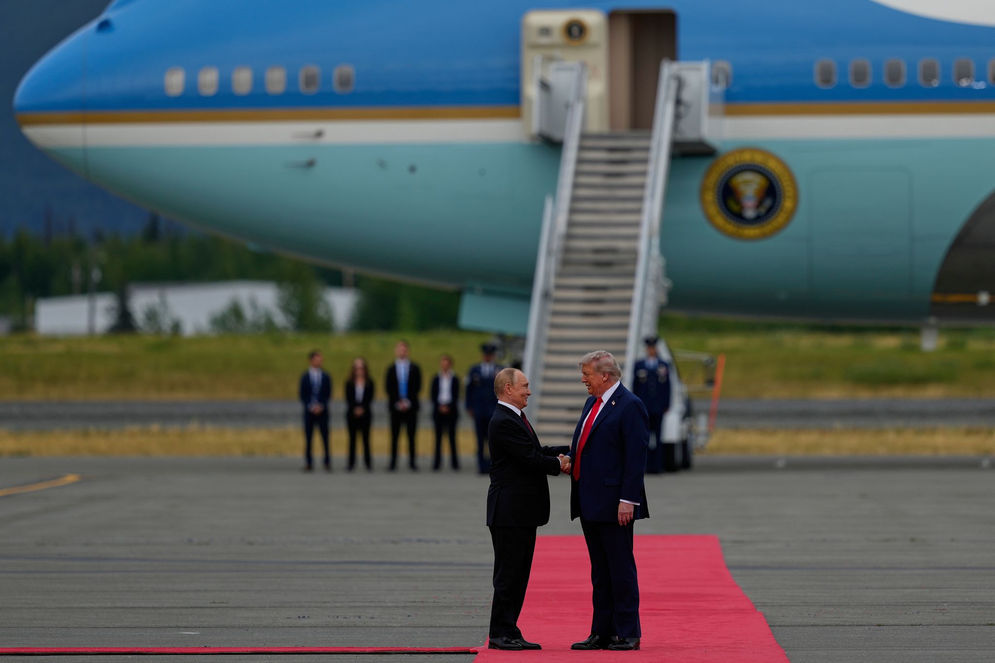 Trump und Putin begrüßen sich mit einem Handschlag.