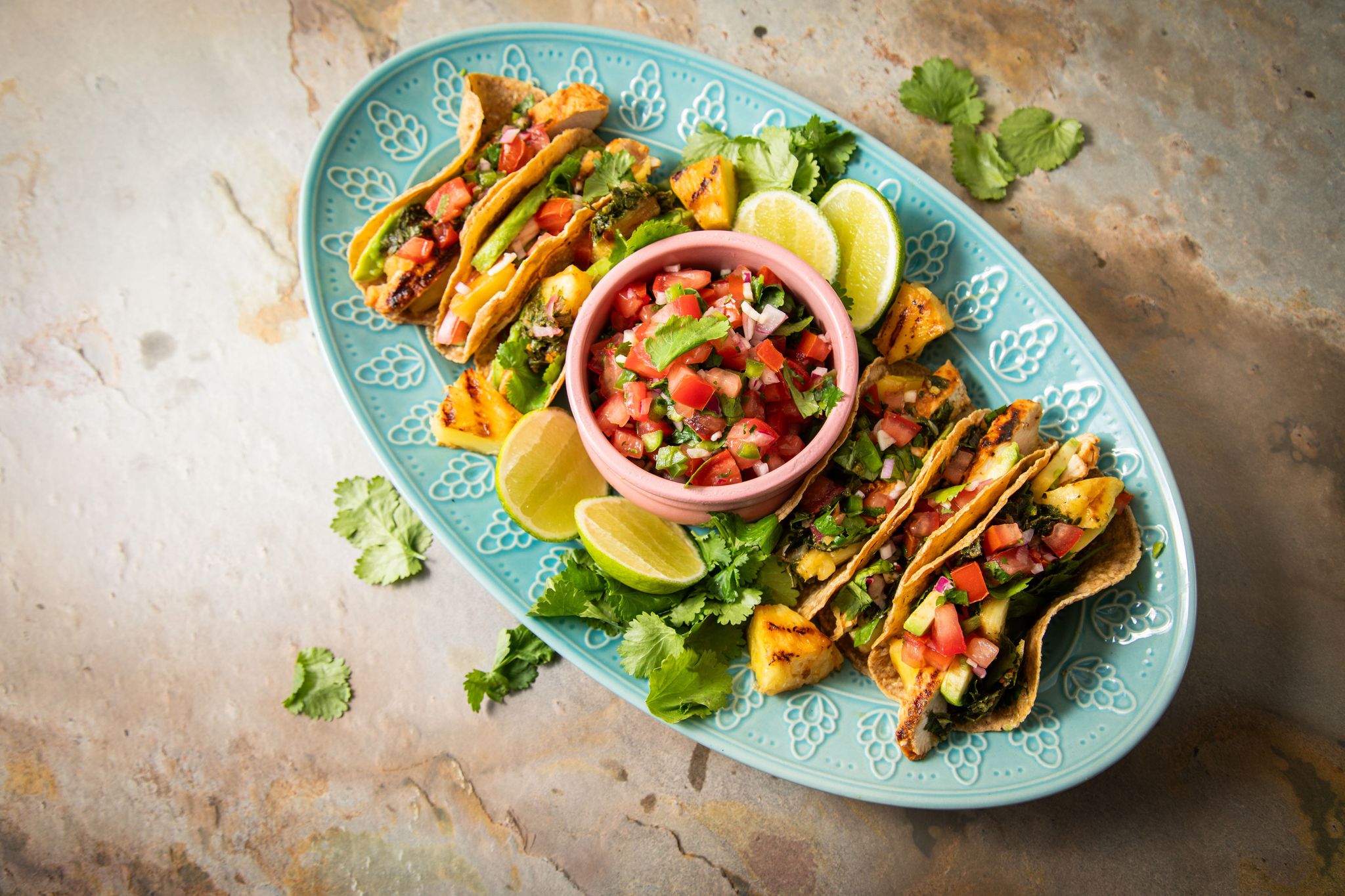 Richtig stilecht werden Hähnchen-Tacos erst mit Zugaben wie der mexikanische Tomatensalsa «Pico de Gallo», argentinischer Kräutersauce «Chimichurri», Avocado, gegrillter Ananas, Koriander und Limetten.