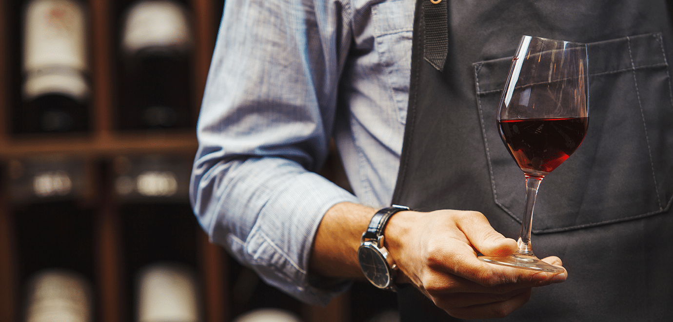 Foto: s:IL21/iStock, ein Sommelier mit einem Glas Rotwein in der Hand
