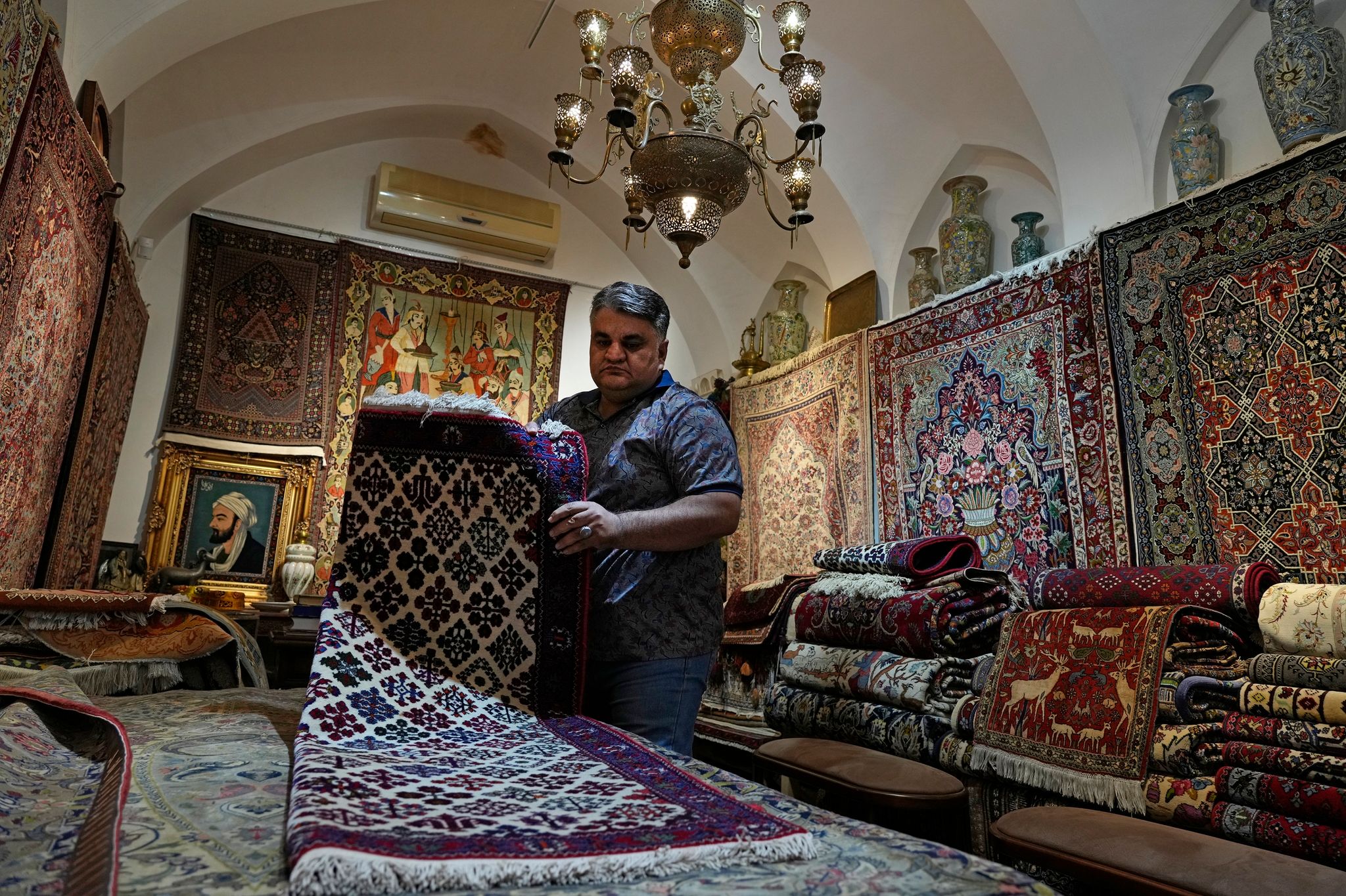Ein iranischer Teppichhändler arbeitet in seinem Geschäft auf dem traditionellen Basar der Stadt Kashan.