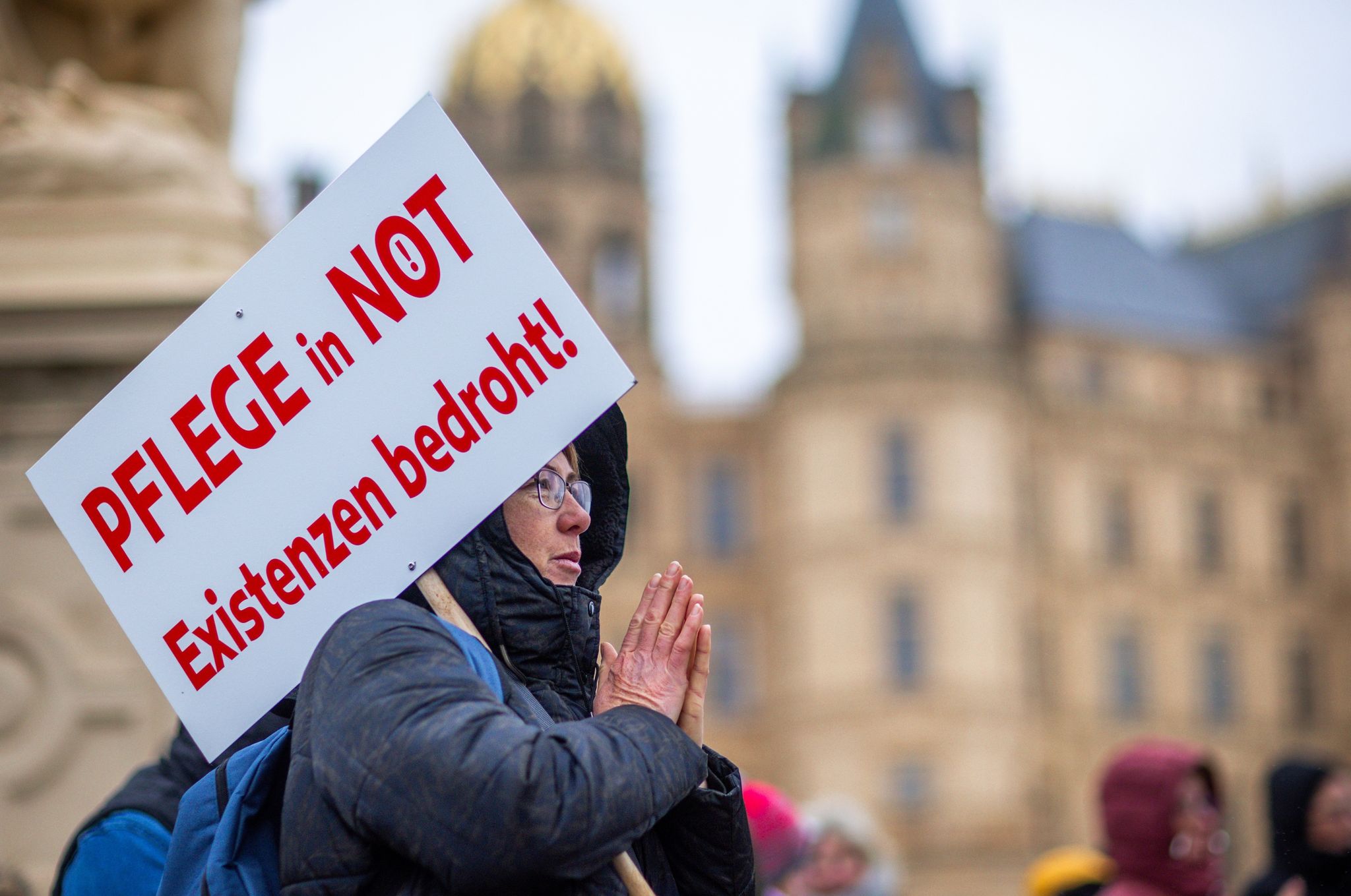 Bei einer Protestaktion vor dem Schweriner Landtag hält eine Teilnehmerin ein Schild mit der Aufschrift «Pflege in Not - Existenzen bedroht!».
