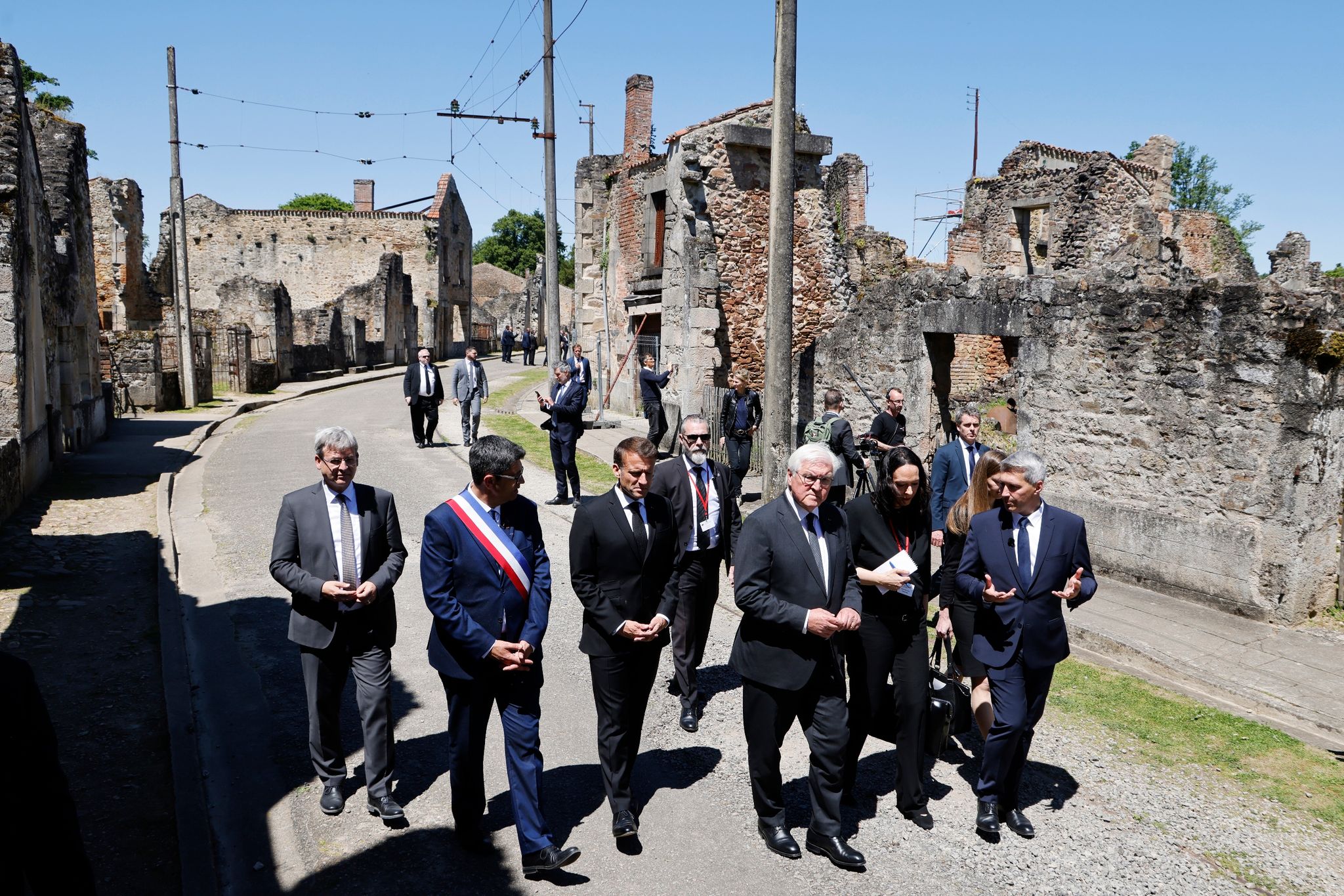 Der französische Präsident Emmanuel Macron und der deutsche Bundespräsident Frank-Walter Steinmeier gehen an Ruinen in Oradour-sur-Glane vorbei.