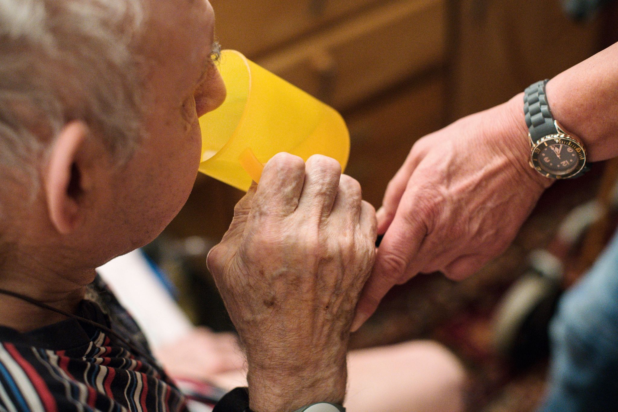 Eine ambulante Pflegerin hilft einem alten Mann bei der Tabletteneinnahme.